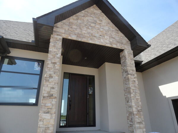 Stacked-stone entry columns with a dark soffit and a wood front door