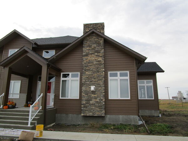 Brown siding house with a tall stone chimney and a covered porch
